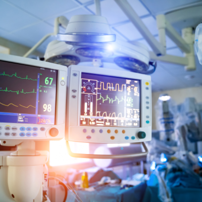 an intensive care ward in a hospital with monitoring screens and staff in blue gowns